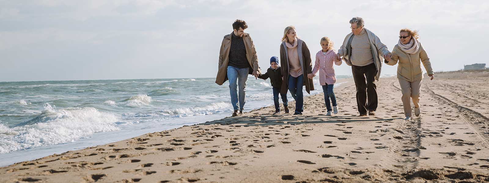 A senior couple is walking the beach with their children and grandchildren, for whom they’ve set up an estate planning trust.